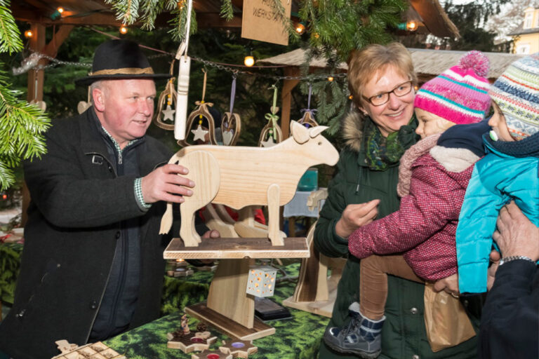 Handwerker zeigt traditionelles Holzhandwerk für Familien am Adventmarkt in Bad Gleichenberg.